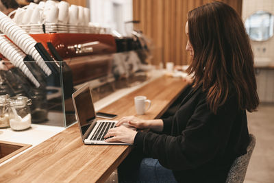 Adult confident business woman freelancer working in a coffee shop cafe using a laptop and phone