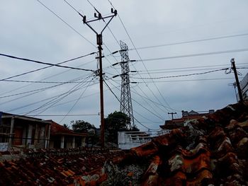 Low angle view of electricity pylon and buildings against sky