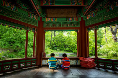 Rear view of boys sitting in gazebo at park