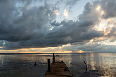 Pier over sea against sky during sunset