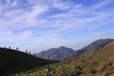 People hiking on mountain against sky