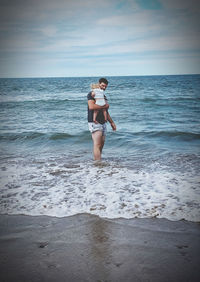 Full length of woman standing on beach against sky