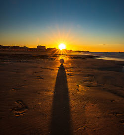 Silhouette person on beach against sky during sunset