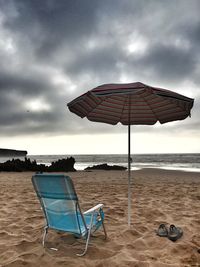 Deck chairs and parasols on beach against sky