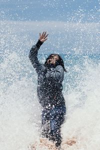 Sea waves splashing on woman standing on shore at beach