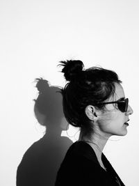 Profile view of woman wearing sunglasses against wall