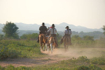 People riding motorcycle on landscape against sky