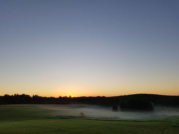 Scenic view of field against clear sky during sunset