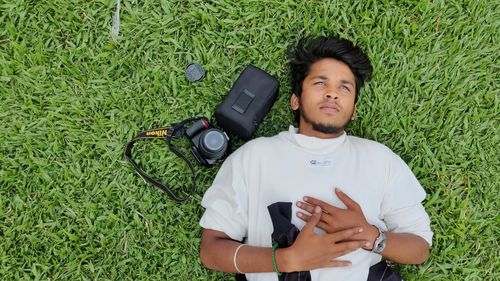 Directly above shot o young man with camera lying down on grassland