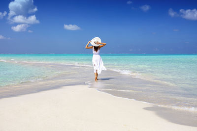 Rear view of woman on beach against sky