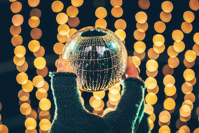 Cropped hand of person holding decoration with reflection