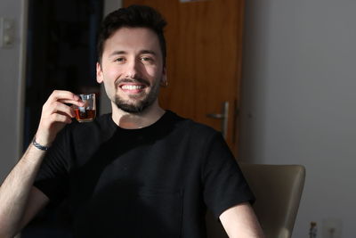Portrait of smiling young man drinking glass