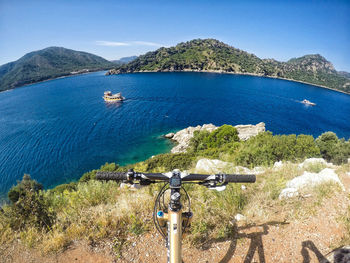 Cropped image of bicycle against river and sky on sunny day