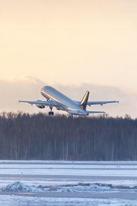 Airplane taking off during a sunset in winter time. aviation concept