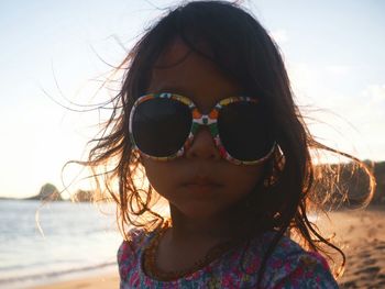 Close-up portrait of smiling mid adult woman against beach