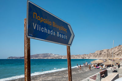 Information sign on beach against clear blue sky