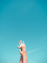 Close-up of hand against blue sky