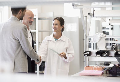 Business people greeting female engineer in manufacturing plant