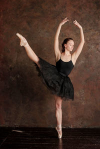 Ballet dancer posing against wall