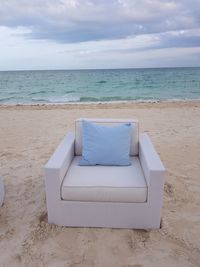 Chair on beach against sky