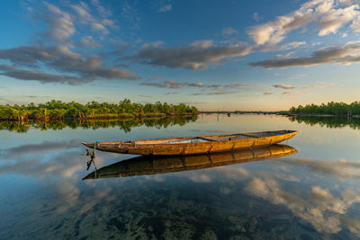 Fishing boat moored on lake against sky