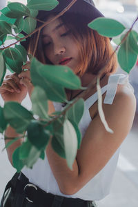 Portrait of a young woman looking at plant