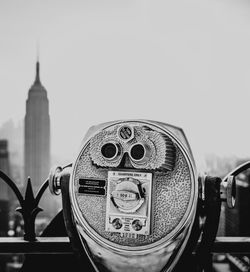 Close-up of coin-operated binoculars against buildings in city