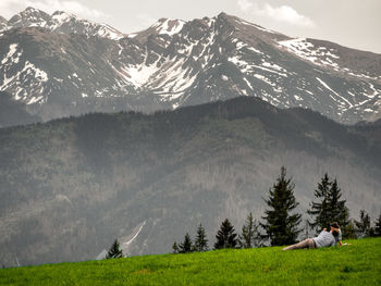 Couple relaxing on green landscape by mountains