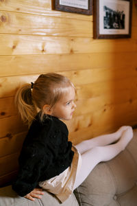 Side view of girl sitting on sofa at home