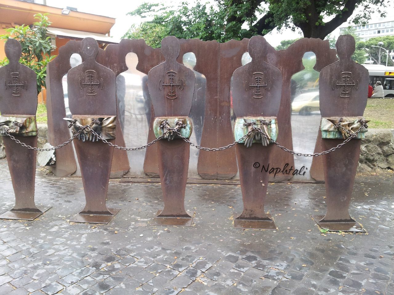 day, sunlight, outdoors, metal, tree, in a row, hanging, shadow, side by side, no people, protection, park - man made space, art and craft, sidewalk, tree trunk, fence, safety, creativity, standing, growth