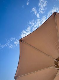 Low angle view of parasol against blue sky