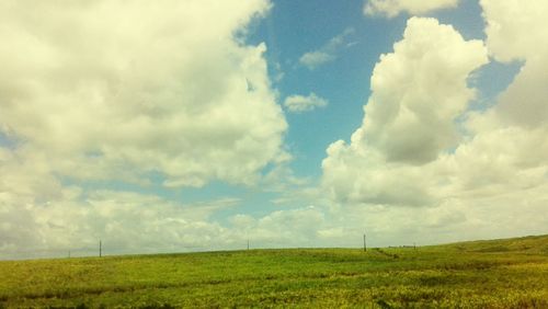 Scenic view of grassy field against cloudy sky