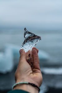 Cropped hand of woman holding ice outdoors