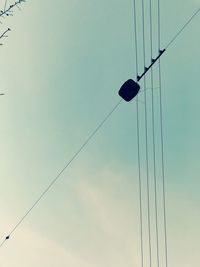 Low angle view of overhead cable cars against sky