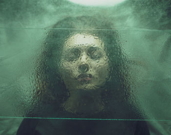 Close-up of woman seen through wet glass