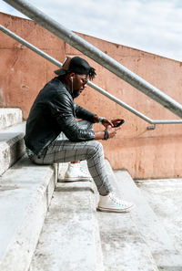 Mid adult man using smart phone while sitting on steps in city