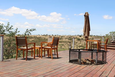 Empty chairs and table against sky