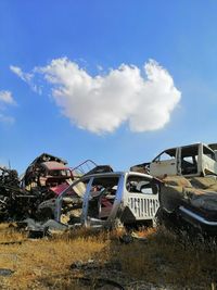 Abandoned cars on field against sky