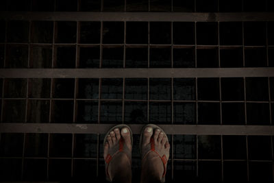 Low section of man standing on tiled floor