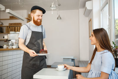 Young couple holding coffee while standing on table