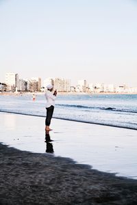 Man standing on beach against clear sky