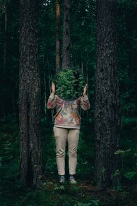 Woman standing by tree trunk in forest