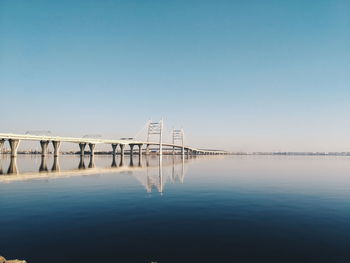 Cranes by lake against clear blue sky