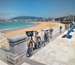 Bicycles on beach by city against clear sky