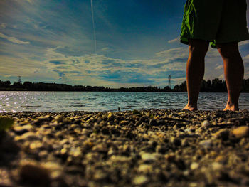 Low section of man standing on beach against sky