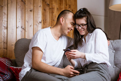 Couple in love sitting on the couch looking at the phone and smiling