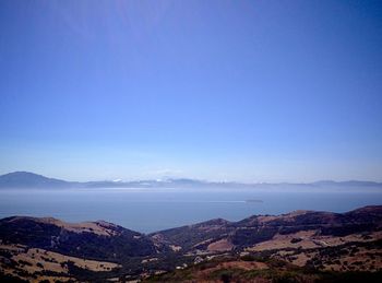 Scenic view of sea and mountains against clear blue sky