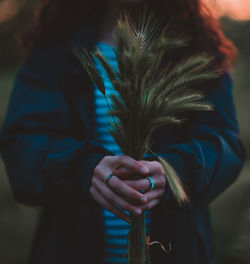 Midsection of woman holding reed during sunset