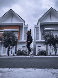 Man standing by house against sky