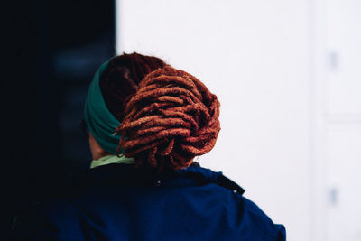 Rear view of woman with dreadlocks against wall